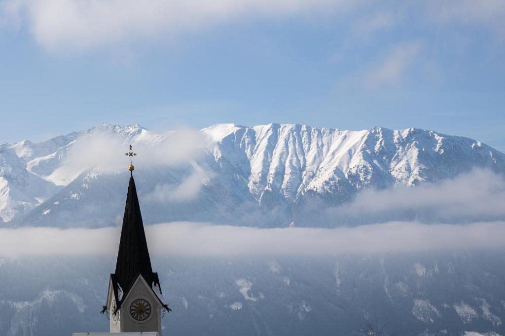 a church with a clock tower in front of a mountain at Wohnung mit Bergblick im Haus Sonne in Reith bei Seefeld