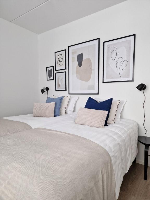 a white bedroom with two beds and pictures on the wall at Huhta Sport in Jyväskylä