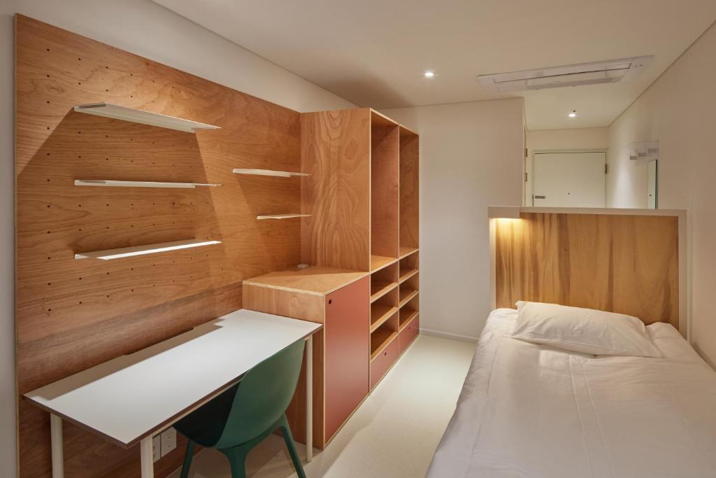 a small room with a bed and a desk in it at Mangrove Sinseol in Seoul