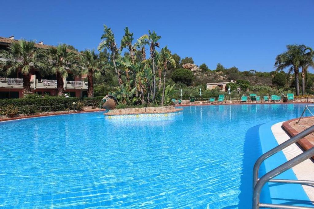 a large swimming pool with blue water in a resort at Rais Gerbi Appartamento in Pollina
