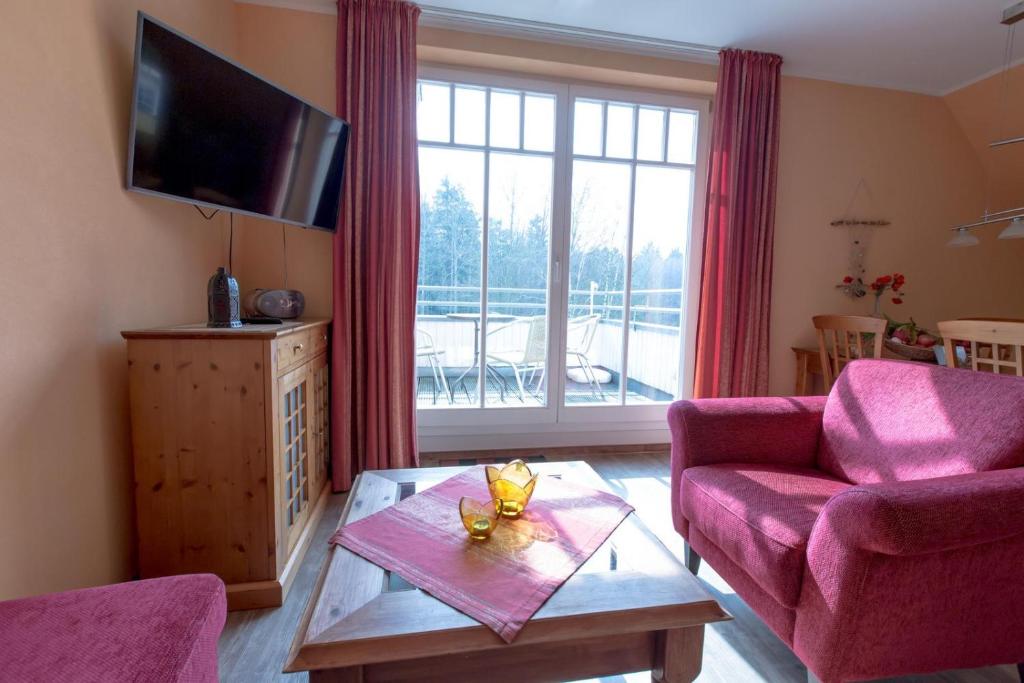 a living room with a pink couch and a table at Villa-Senta-Apartment-9 in Kühlungsborn