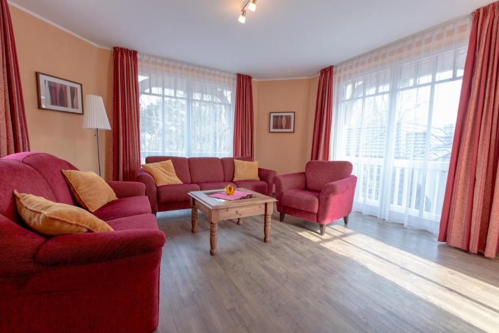 uma sala de estar com duas cadeiras vermelhas e uma mesa em Villa-Senta-Apartment-11 em Kühlungsborn