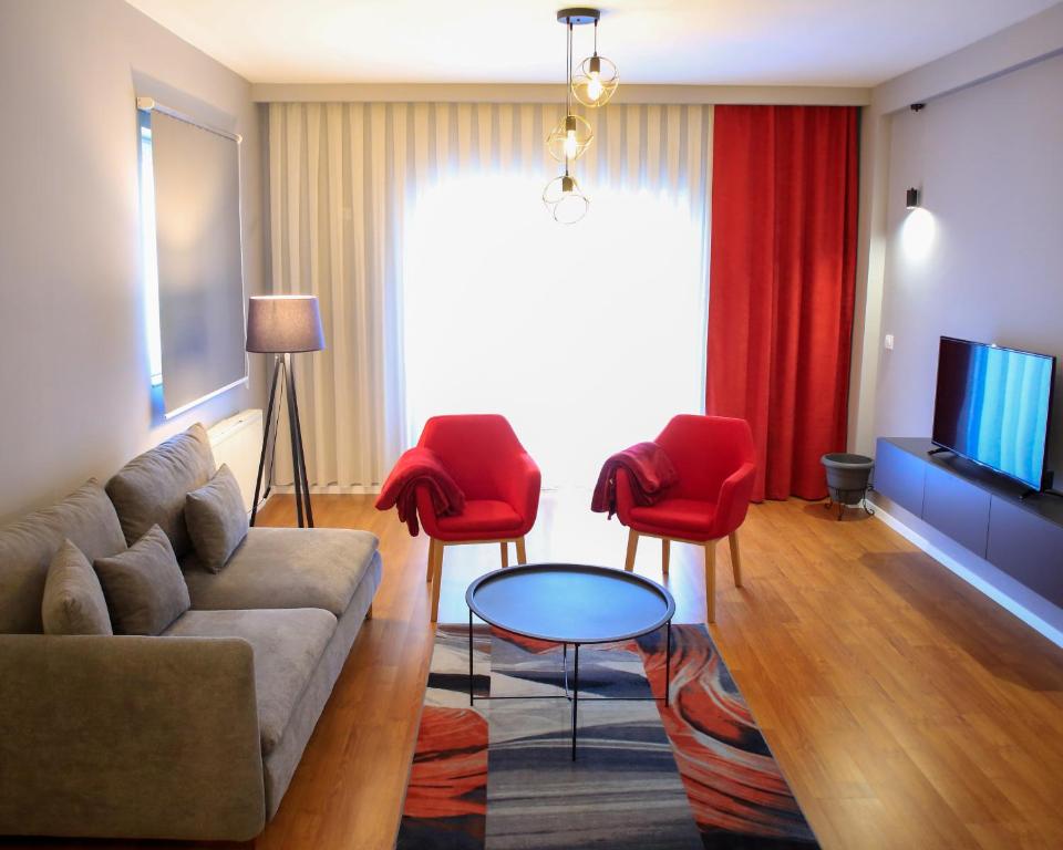 a living room with a couch and red chairs at Parta Apartment in Prishtinë