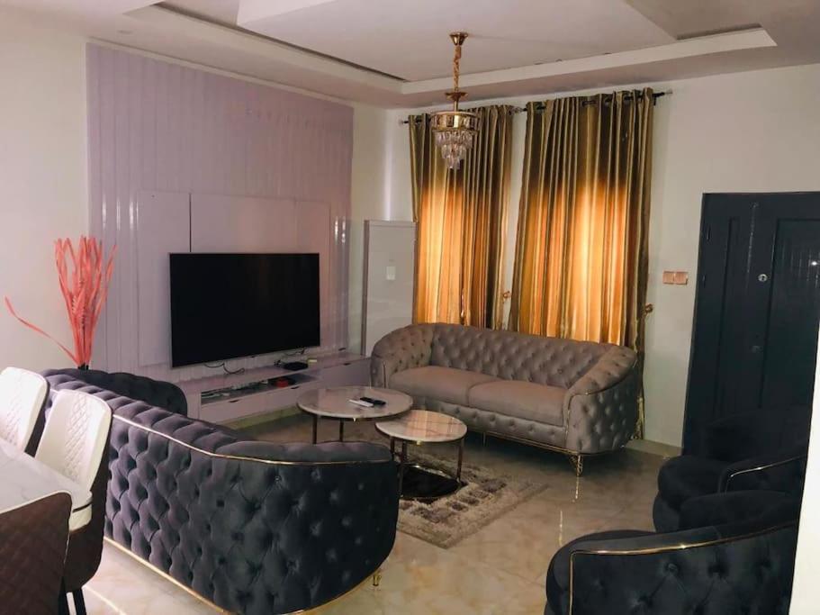 a living room with a couch and a tv at Beautiful 4-Bedroom House in Ogombo