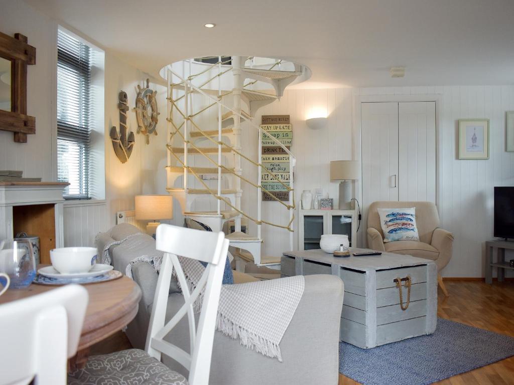 - un salon avec une table et un escalier en colimaçon dans l'établissement Swallows Cottage, à Churston Ferrers