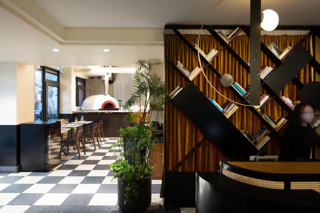 a restaurant with a checkered floor and a wall with books at Theodor Brown Rothschild Tel-Aviv, a member of Brown Hotels in Tel Aviv