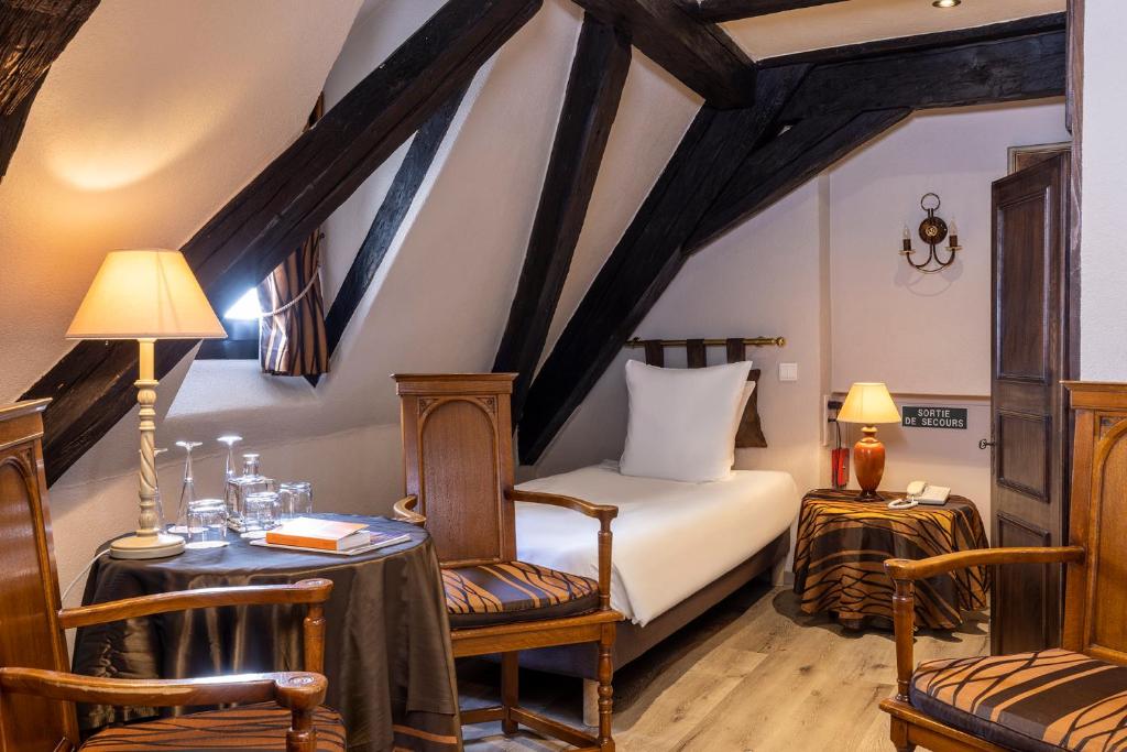 a bedroom with a bed and a table and chairs at Hotel Restaurant Le Maréchal - Teritoria in Colmar