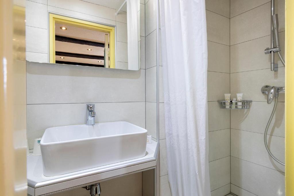 a white bathroom with a sink and a shower at Hotel Restaurant Le Maréchal - Teritoria in Colmar