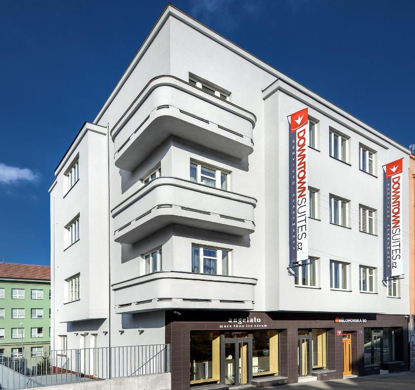 ein weißes Gebäude mit zwei orangenen Schildern darauf in der Unterkunft DownTown Suites Belohorska in Prag