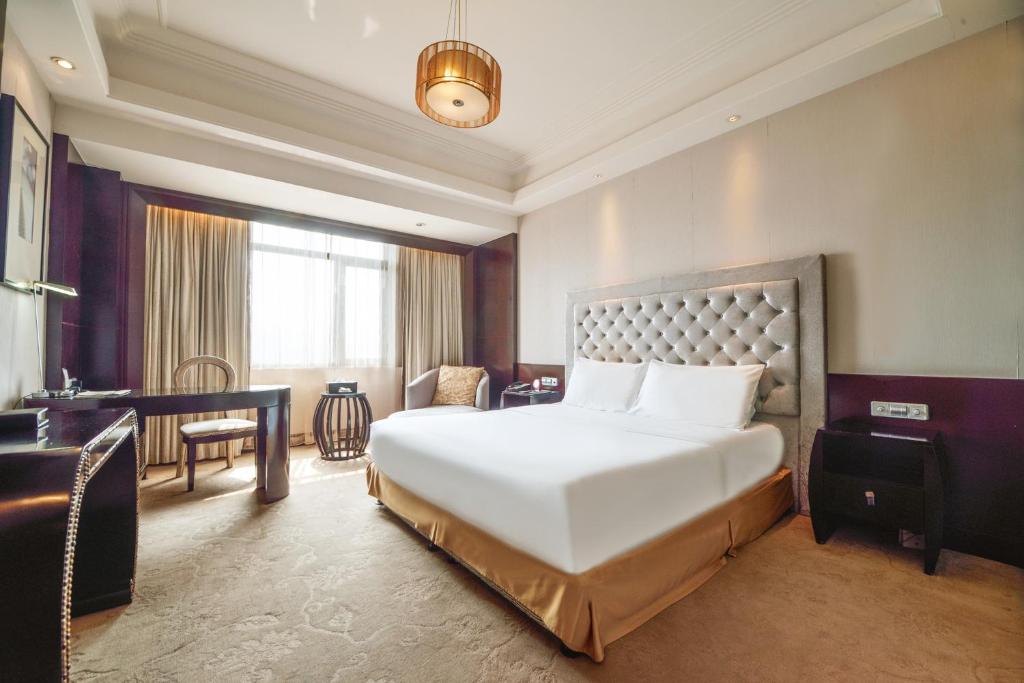 a bedroom with a large white bed and a desk at S&N Hotel Dalian in Wafangdian