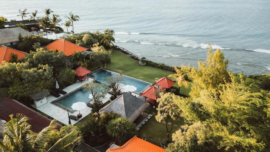 an aerial view of a house with a swimming pool and the ocean at Uluwatu Cottages in Uluwatu