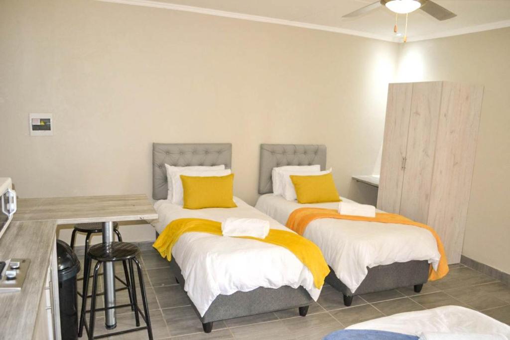 a bedroom with two beds with yellow pillows at Bethlehem Sundowners Guesthouse in Bethlehem
