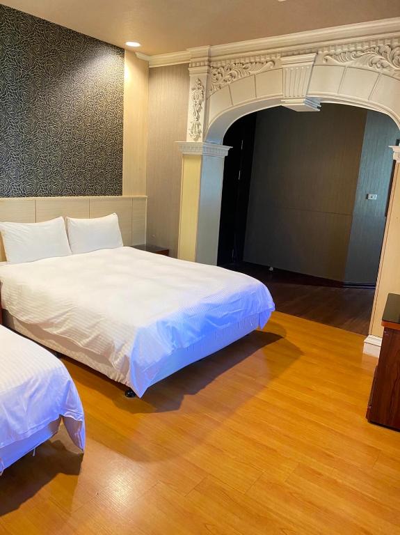 a bedroom with two beds in a room with wood floors at The Prince Hotel in Tainan
