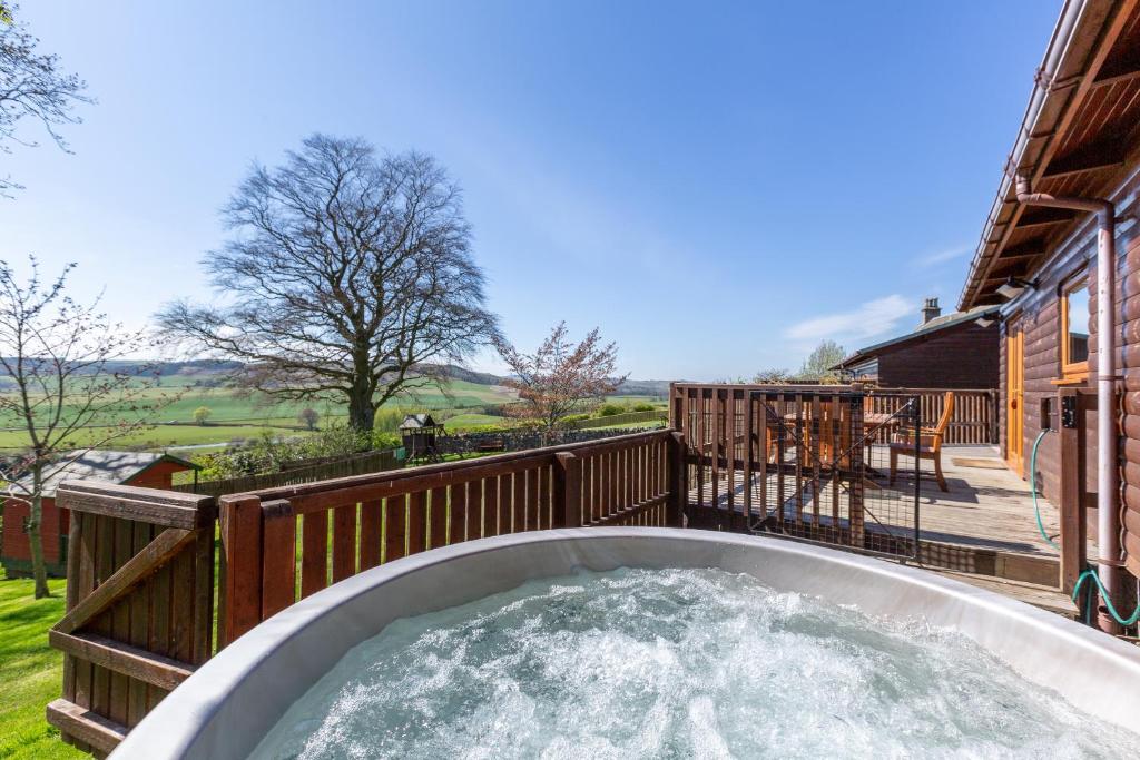 a hot tub on the deck of a house at Douglas Fir Lodge with Hot tub in Cupar