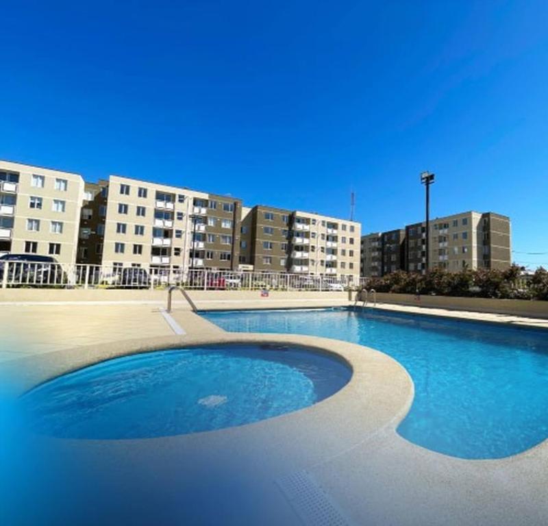 uma grande piscina em frente a alguns edifícios em Apartment With Pool Access em Temuco
