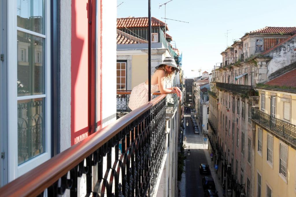 a woman standing on a balcony looking out over a city at Hotel Lis Baixa in Lisbon