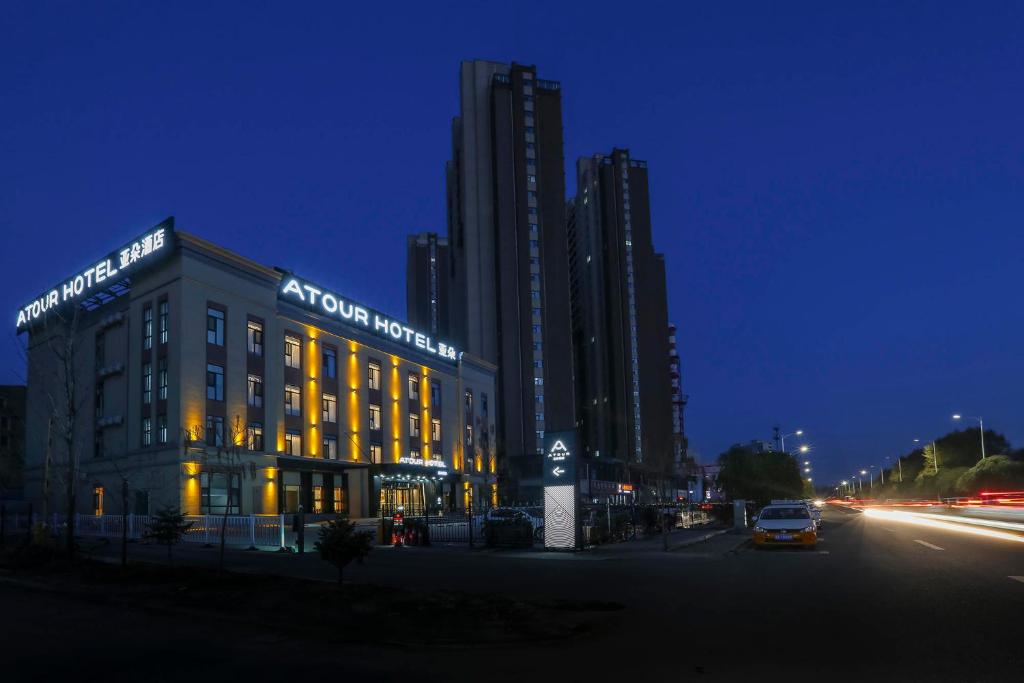 Atour Hotel International Convention and Exhibition Center Changchun في تشانغتشون: مبنى عليه علامة في الليل