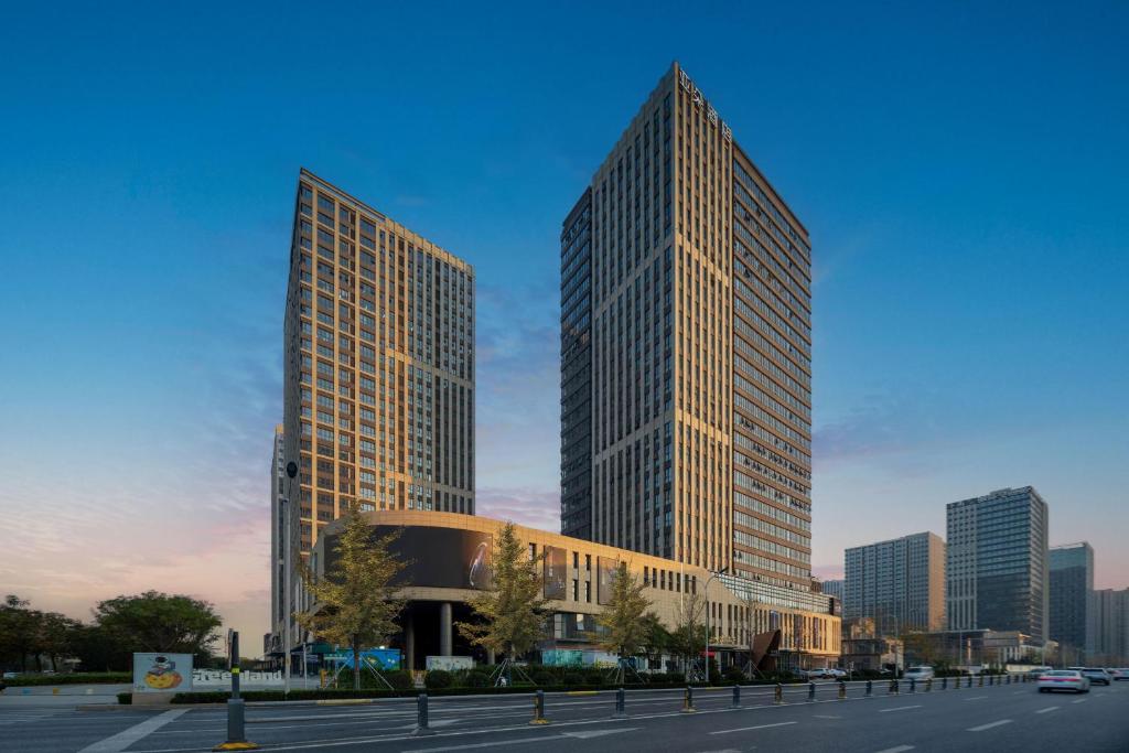 twee hoge gebouwen in een stad met een straat bij Atour Hotel Jinan West Railway Station in Jinan