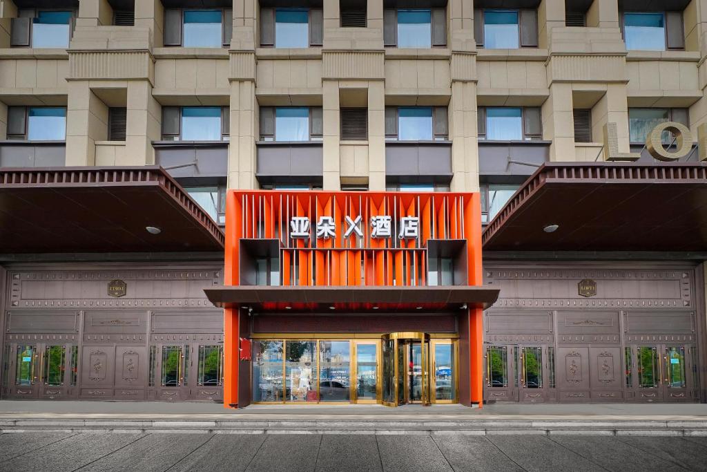 un gran edificio naranja con un cartel. en Atour X Hotel Harbin West Railway Station en Harbin