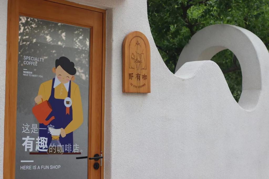 a sign on a door with a woman holding a camera at Encounter Garden Great Wall Holiday Guesthouse in Beijing