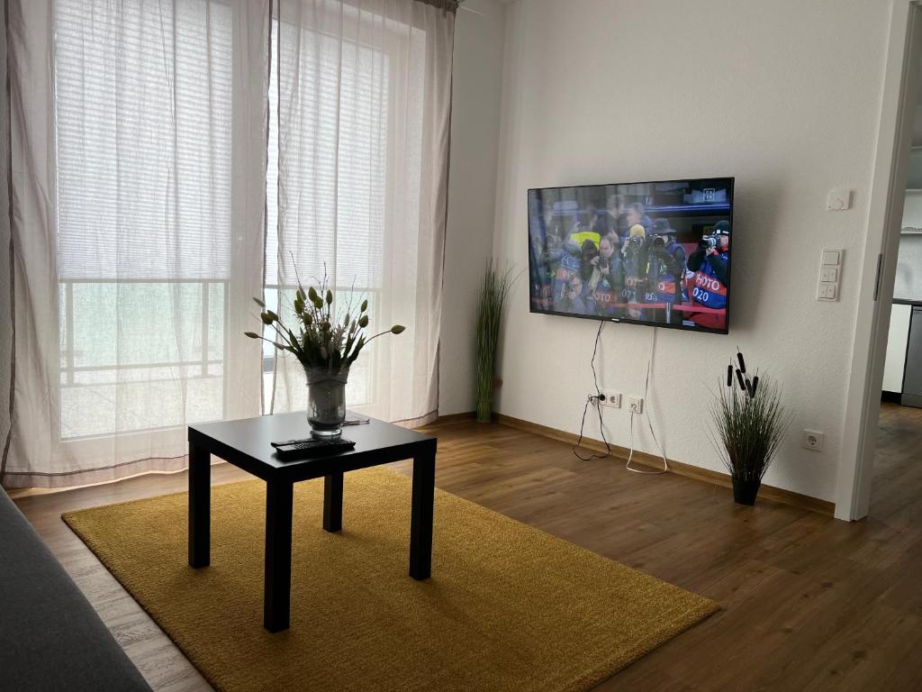 a living room with a table and a tv on the wall at ApartHotel Roxheim in Roxheim