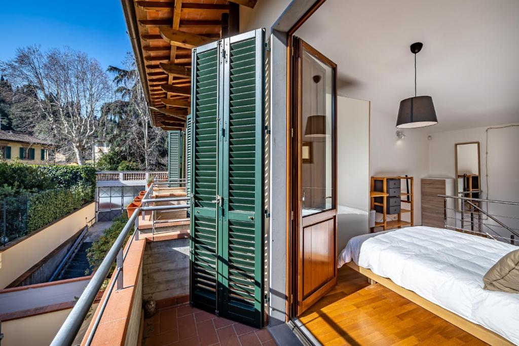 a bedroom with green shutters and a bed on a balcony at YID Oltrarno segreto in Florence