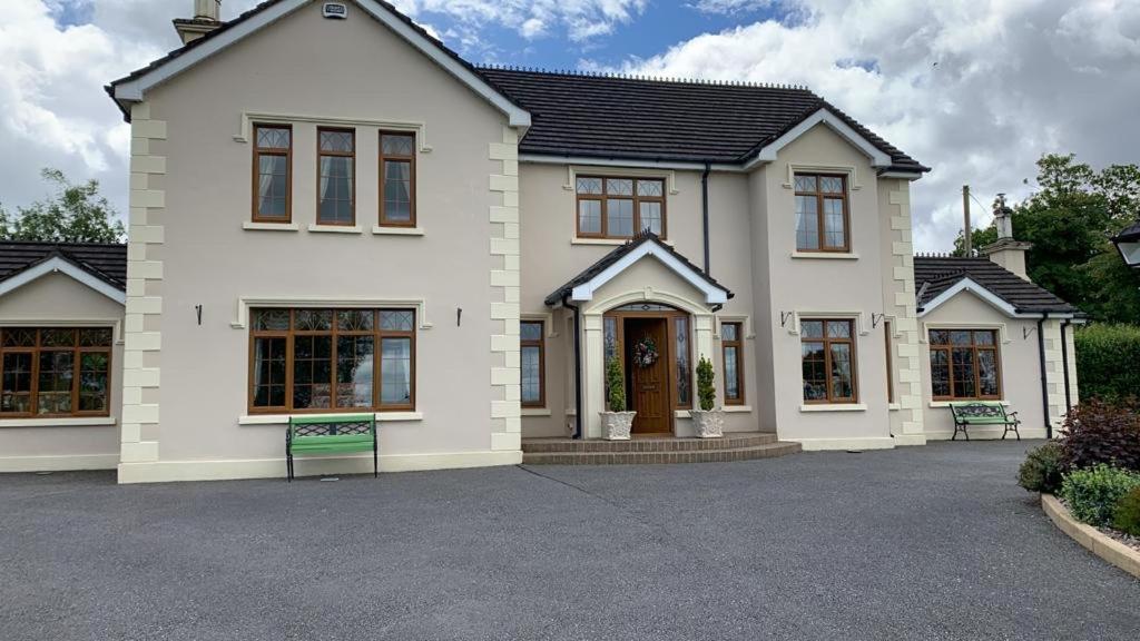 Uma casa branca com um banco à frente. em Mayrone House B&B em Donegal