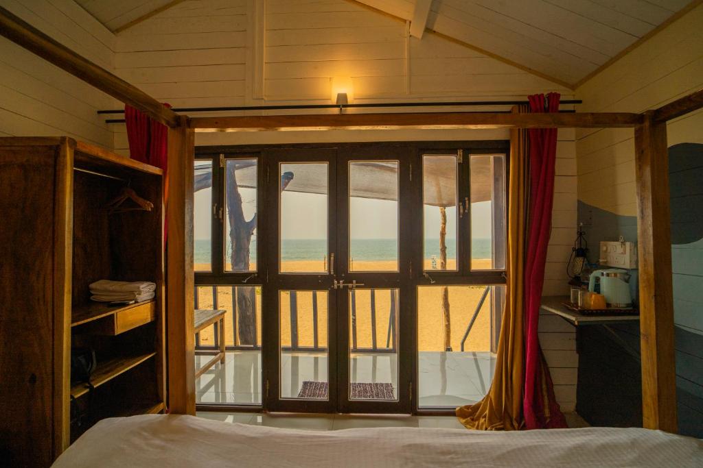 a bedroom with a window with a view of the beach at Shambho Retreat in Canacona