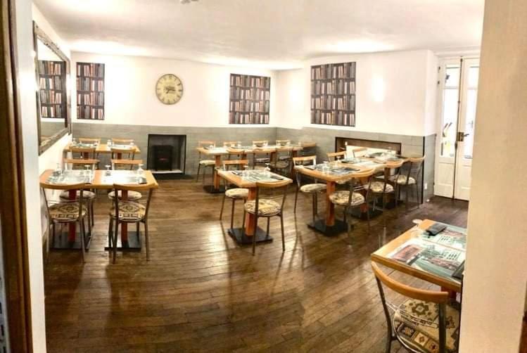 a restaurant with tables and chairs and a clock on the wall at Hotel du Centre in Châlus