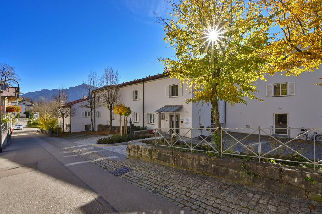 ein weißes Gebäude auf einer Straße mit einem Baum in der Unterkunft Gästehaus Sankt Ulrich in Füssen