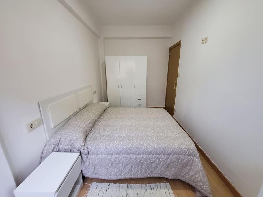 een kleine slaapkamer met een bed en een kast bij Acogedor estudio en Estribela in Marín