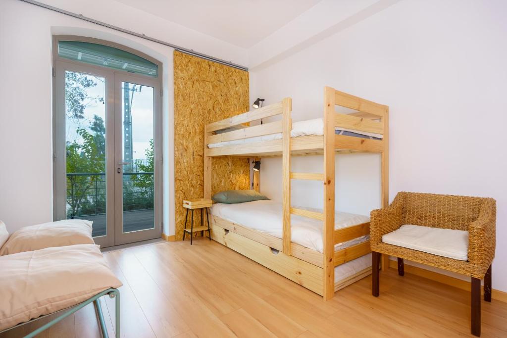 a bedroom with two bunk beds and a chair at Casa Verde Sal in Alcácer do Sal