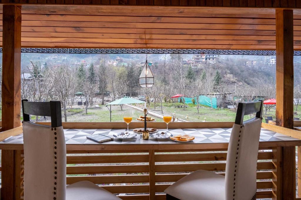 una mesa con 2 sillas y una ventana con vistas. en Woodville, en Manali