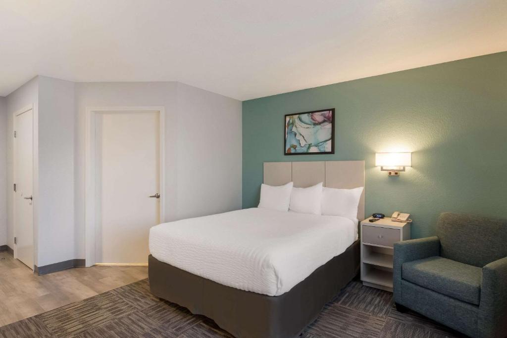 a hotel room with a bed and a chair at MainStay Suites Omaha Old Mill in Omaha