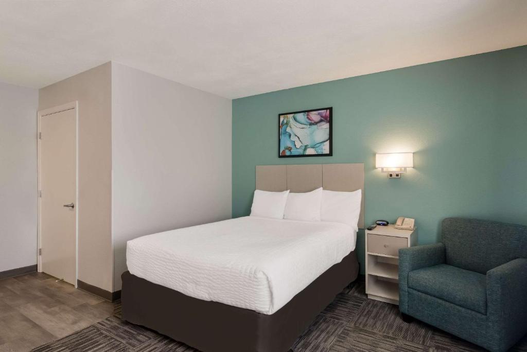 a bedroom with a bed and a chair in a room at MainStay Suites Omaha Old Mill in Omaha