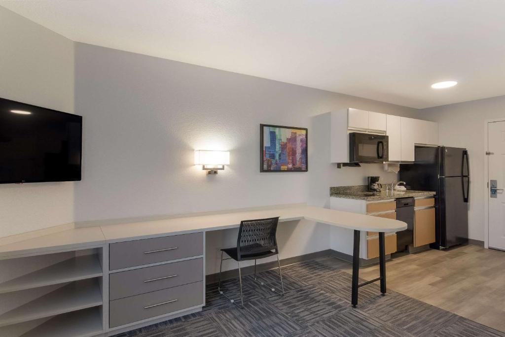 a kitchen with a desk and a table with a chair at MainStay Suites Omaha Old Mill in Omaha