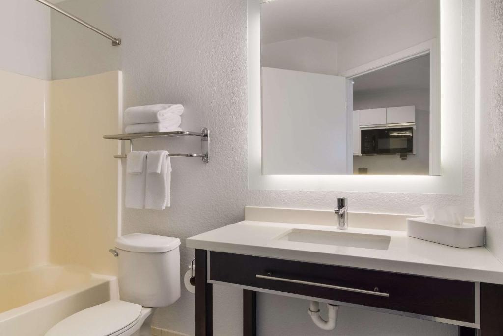 a bathroom with a sink and a toilet and a mirror at MainStay Suites Omaha Old Mill in Omaha