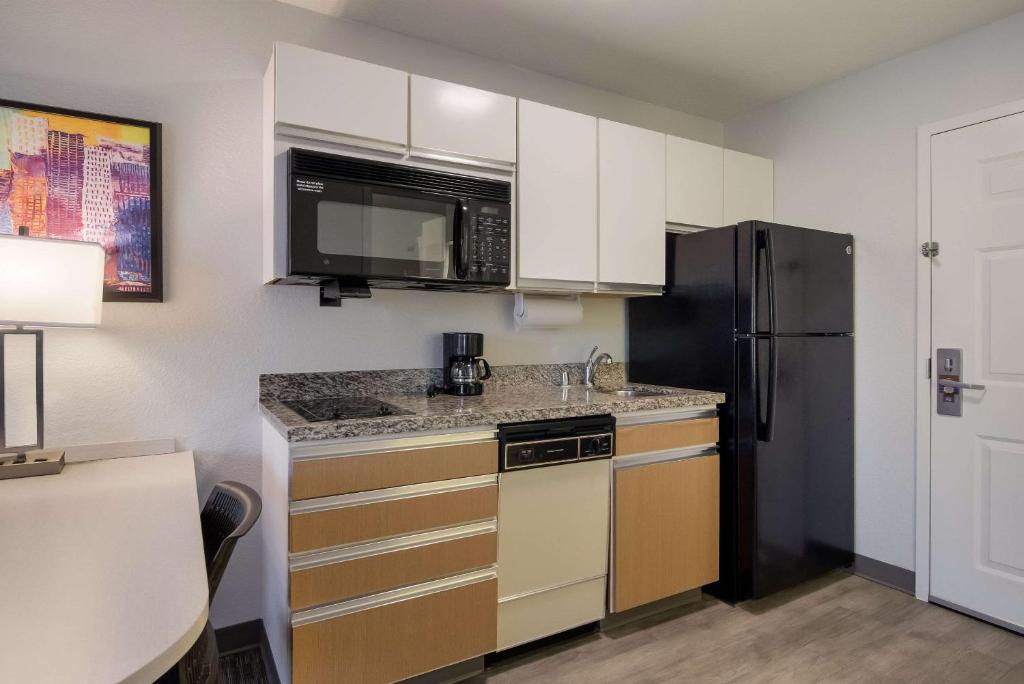 a small kitchen with a refrigerator and a microwave at MainStay Suites Omaha Old Mill in Omaha