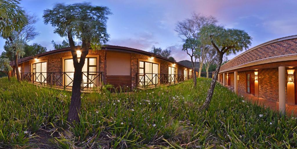 a house in the grass next to a building at The Venue Country Hotel & Spa in Hartbeespoort