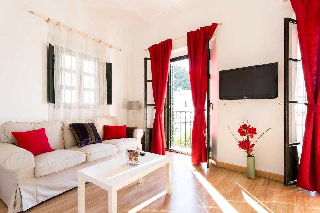 ein Wohnzimmer mit roten Vorhängen und einer weißen Couch in der Unterkunft Plaza de Santa Cruz in Sevilla
