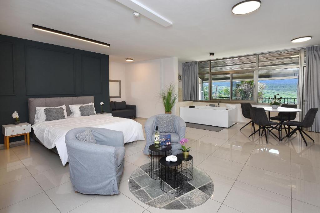 a bedroom with a bed and a table and chairs at אדם וחווה - סוויטות מפנקות עם ג'קוזי פרטי ובריכה במתחם מול נוף גלילי מושלם in Gornot HaGalil