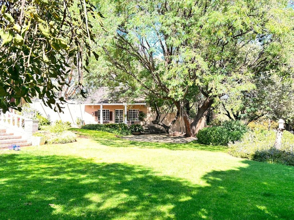 una casa con un giardino verde con un albero di Farm stay at Saffron Cottage on Haldon Estate a Bloemfontein