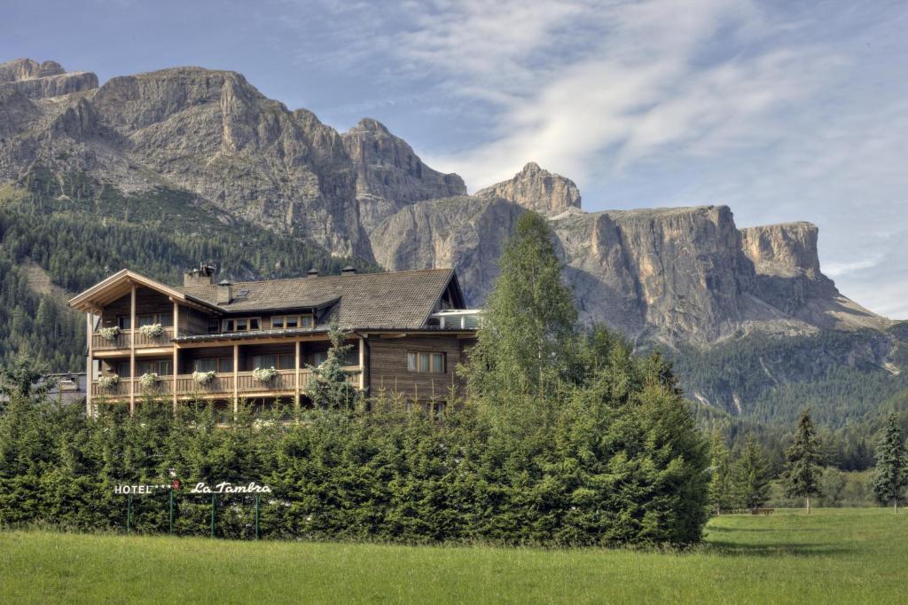 a large house in front of a mountain at Hotel La Tambra in Corvara in Badia
