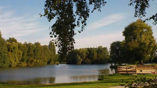 a lake with a wooden fence next to a park at Les Insolites du vélodrome d&#39;Albert in Albert