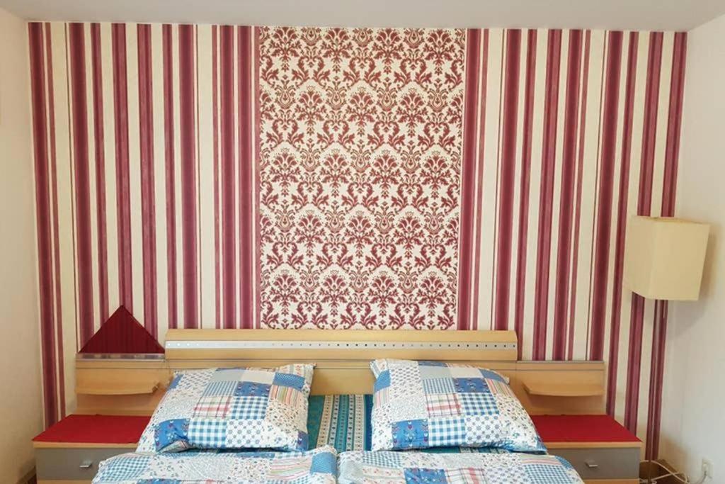 a bedroom with a bed and a red and white wallpaper at 2 Rooms Apartment in Triberg in Triberg