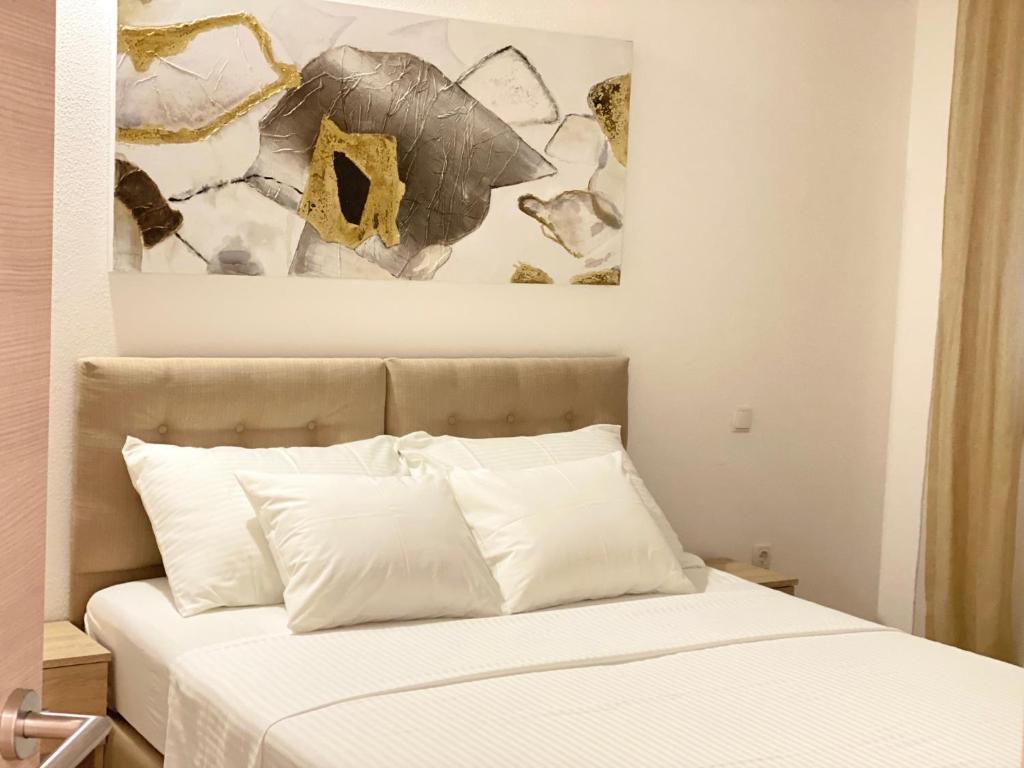 a bed with white pillows and a painting above it at Apartment Komljenovic in Pula