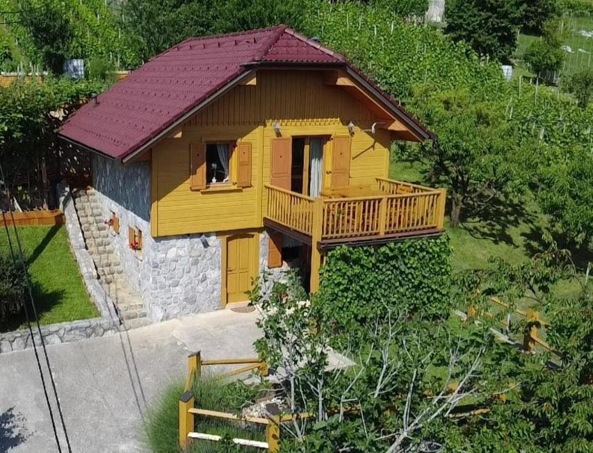 una pequeña casa amarilla con balcón en una colina en Vineyard cottage Stopar, en Straža