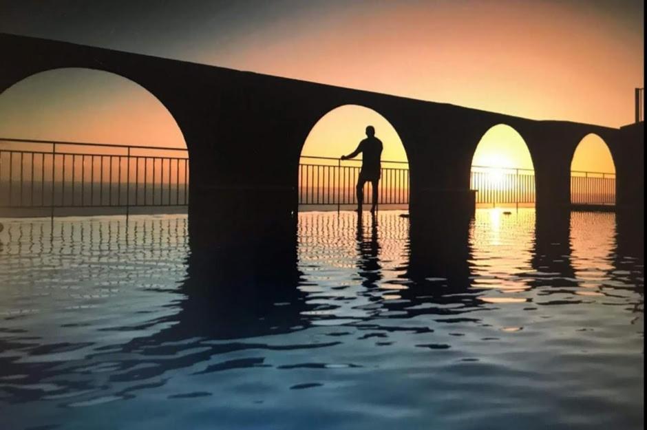 un hombre parado en el agua bajo un puente en La Muralla Apartamentos, en Puerto Naos