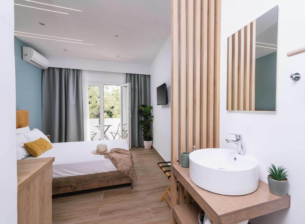 Ermis Luxury Suites & Apartments في أمودارا هيراكليو: غرفة نوم بسرير كبير ومغسلة