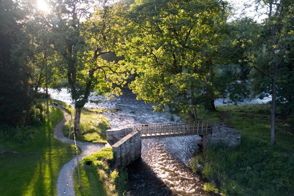 a bridge over a river with trees and a path at Ribblesdale Park in Gisburn